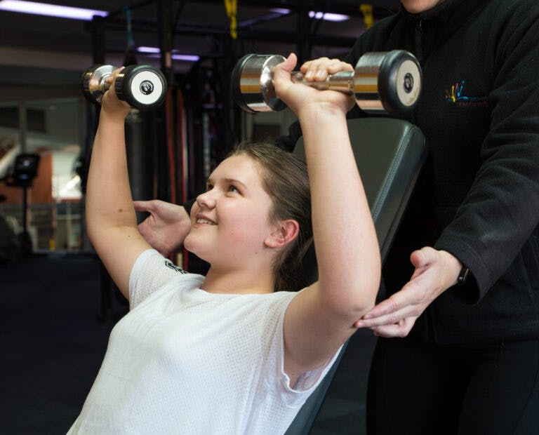 Female youth lifting weights in gym